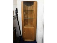 An Ercol elm corner display cabinet with lighting, 76.75in tall x 28.25in at widest x 185in deep, sc