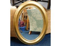 A decorative oval gilt framed bevelled edge mirror