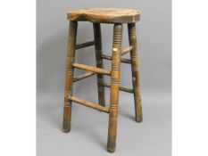 A 19thC. oak bum stool, 28.5in high, one stretcher