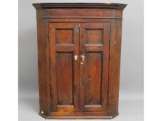 A Georgian oak corner cupboard with ivory escutche