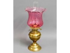 A brass oil lamp with cranberry glass shade, 18.5i