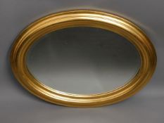 A decorative oval gilt framed bevelled edge mirror