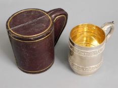 A gilt lined silver christening cup with leather c