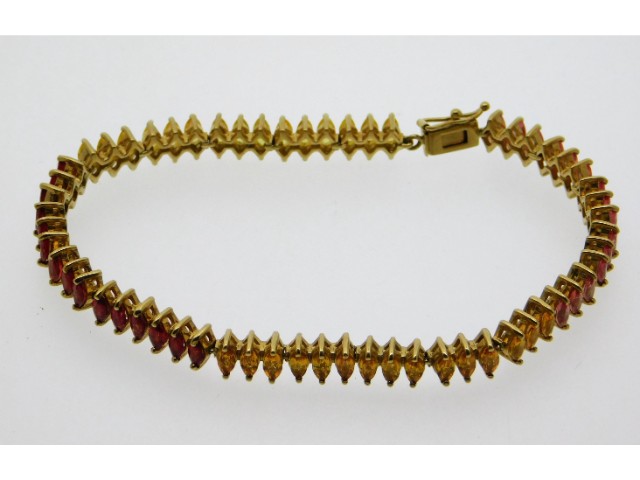 A 9ct gold bracelet set with marquise cut red, yel