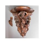 A 19thC. carved walnut wall bracket with winged ch