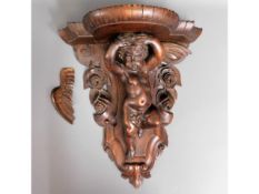 A 19thC. carved walnut wall bracket with winged ch