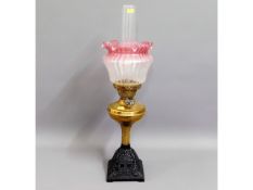 A Victorian brass oil lamp with frosted, cranberry