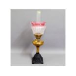 A Victorian brass oil lamp with frosted, cranberry