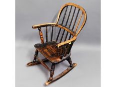 A 19thC. child's elm seated rocking chair, 25in hi