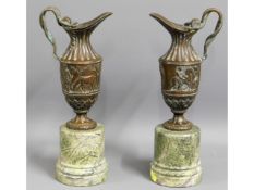 A pair of bronze ewers on marble plinths, 14.75in