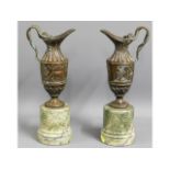 A pair of bronze ewers on marble plinths, 14.75in