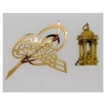 A 14ct gold charm twinned with a 14ct gold brooch,