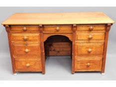 An antique light oak knee hole desk with nine drawers, 50in wide x 28in high x 21.5in