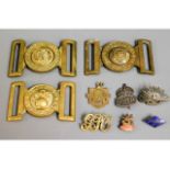 Three brass military buckles, a silver ARP badge,