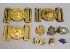 Three brass military buckles, a silver ARP badge,