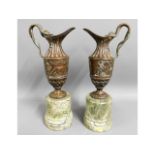 A pair of decorative, bronze ewers on marble plint