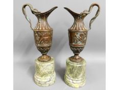 A pair of decorative, bronze ewers on marble plint