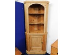 A waxed pine corner cupboard with brass door knob,