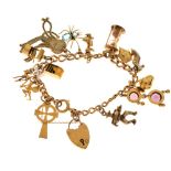 Yellow metal curb link charm bracelet with 9ct gold padlock and fifteen assorted charms, 39.8g gross