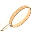 9ct gold snap bangle of hollow design, one half with foliate scroll engraving, 14.8g approx