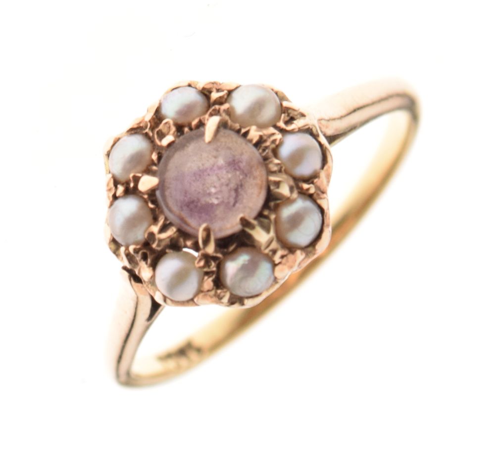 Yellow metal dress ring set amethyst-coloured stone within seed pearls, shank stamped 18ct, size