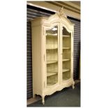 Continental carved wood bookcase with two bevelled glazed doors and standing on four shaped feet,