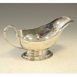 George V silver sauce boat having ribbed scroll handle and standing on a pedestal base, Birmingham