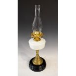 Late Victorian brass oil lamp with white glass reservoir and standing on a black ceramic base, lacks