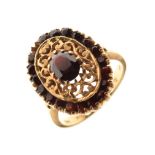 Yellow metal and red garnet-coloured stone dress ring with faceted oval stone and matching border,