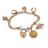 18ct gold curb link bracelet set with assorted gold and yellow metal charms and a plated padlock,