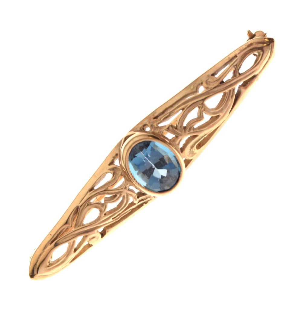 9ct gold bar brooch of pierced foliate scroll design set central faceted oval blue stone, 4.5cm