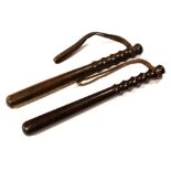 Two wooden truncheons, both having leather wrist straps to grips Condition: One having chunk missing