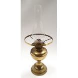 A brass oil lamp with glass chimney.