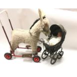 A vintage child's push-along dolls pram together a push along ride on donkey