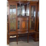 Edwardian mahogany bow front ornate display case with glassed doors and mirror back, standing on