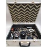 A collection of camera lenses and accessories in a metal flight case.