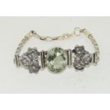 A silver bracelet with large faceted green amethyst.