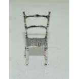 A silver miniature chair in Rene Mcintosh style.