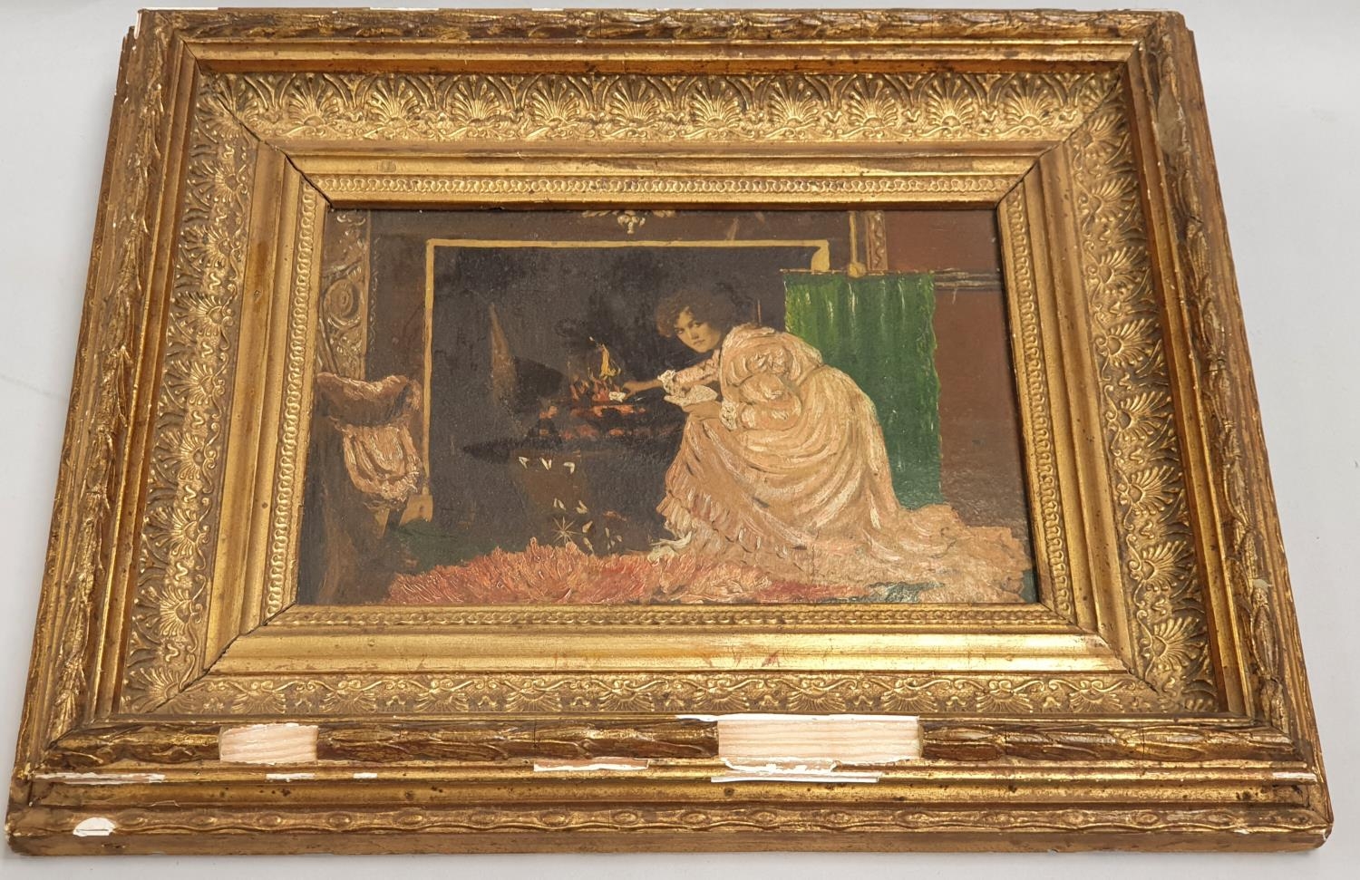 Gilt framed oil on board of a lady by a fireplace. 27.5 x 34.5cm.