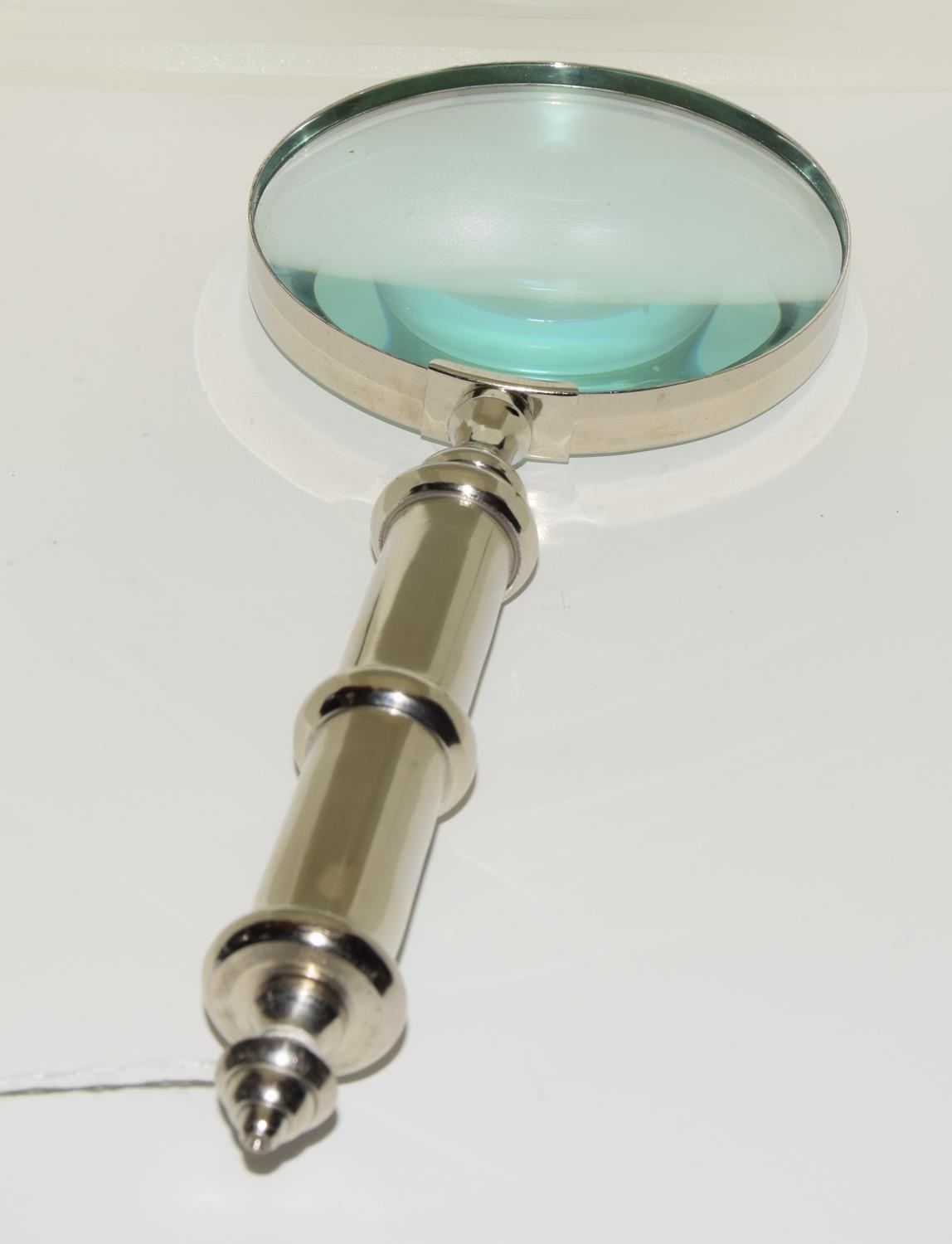 A large hand held magnifying glass with a brushed steel case.