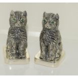 A pair of silver plated cat condiments with emerald eyes.