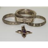 Four silver and white metal bangles together with a garnet and amethyst cross.