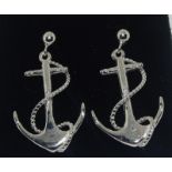 A pair of silver anchor style earrings.