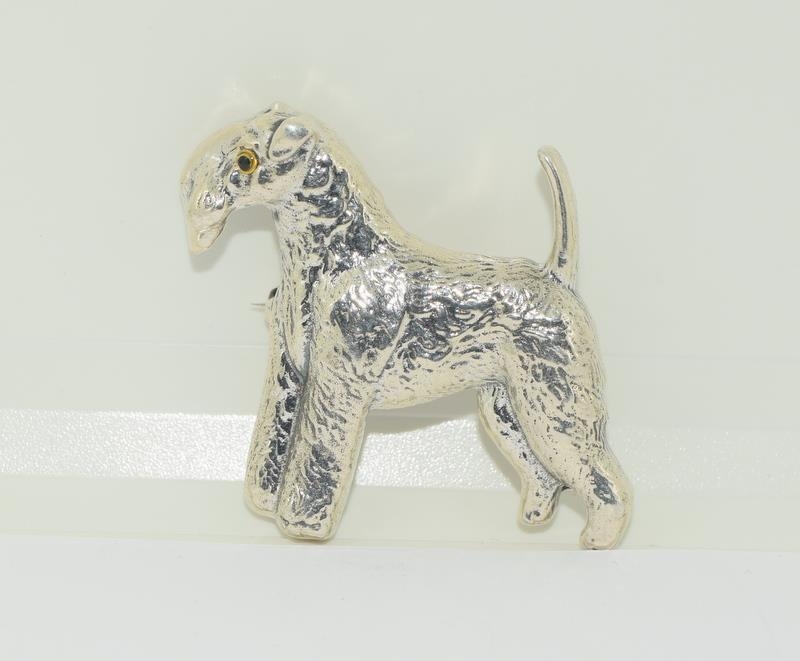 A silver dog brooch with glass eyes.