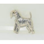 A silver dog brooch with glass eyes.