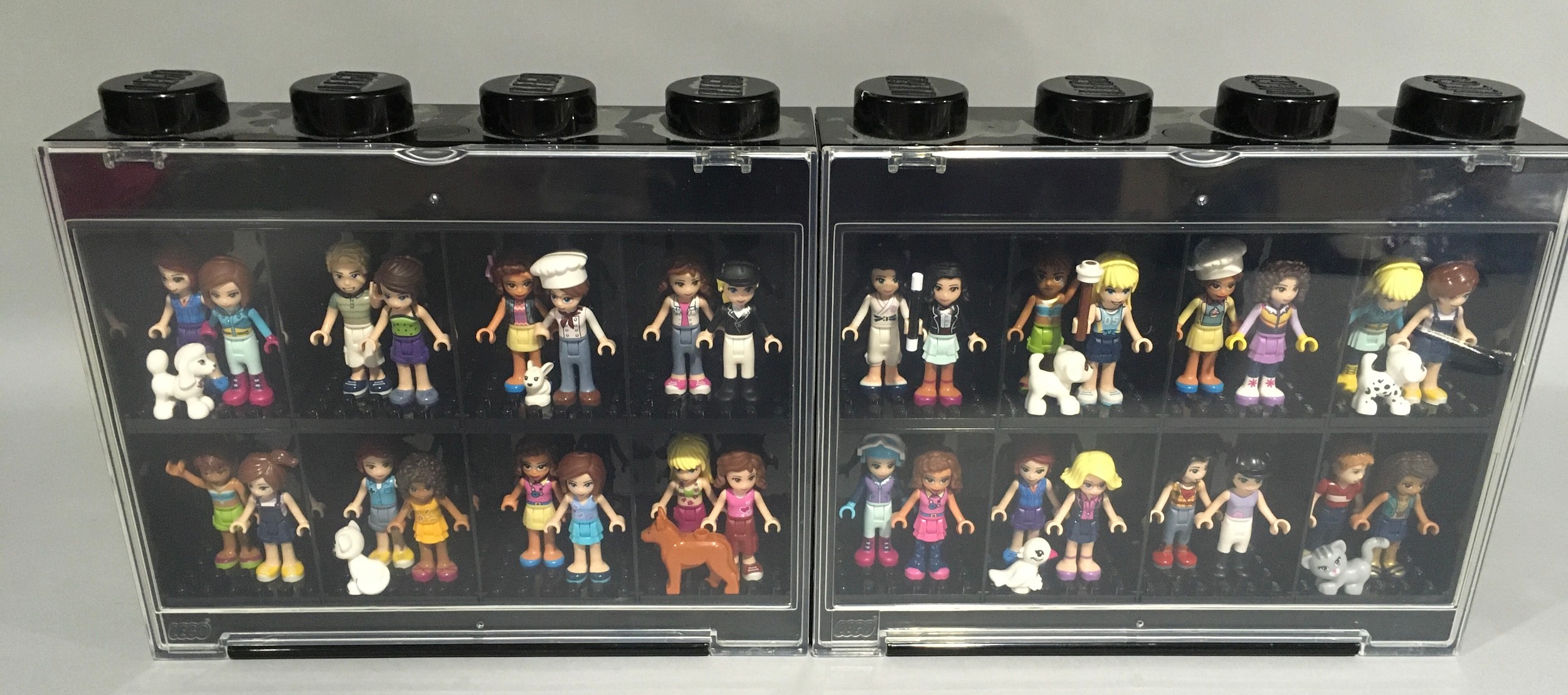 32 Lego Friends Minifigures with some animals and accessories in display cases.