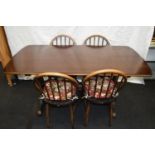 Ercol oak dining table c/w four stick back chairs. 150cm x 75cm x 70cm tall