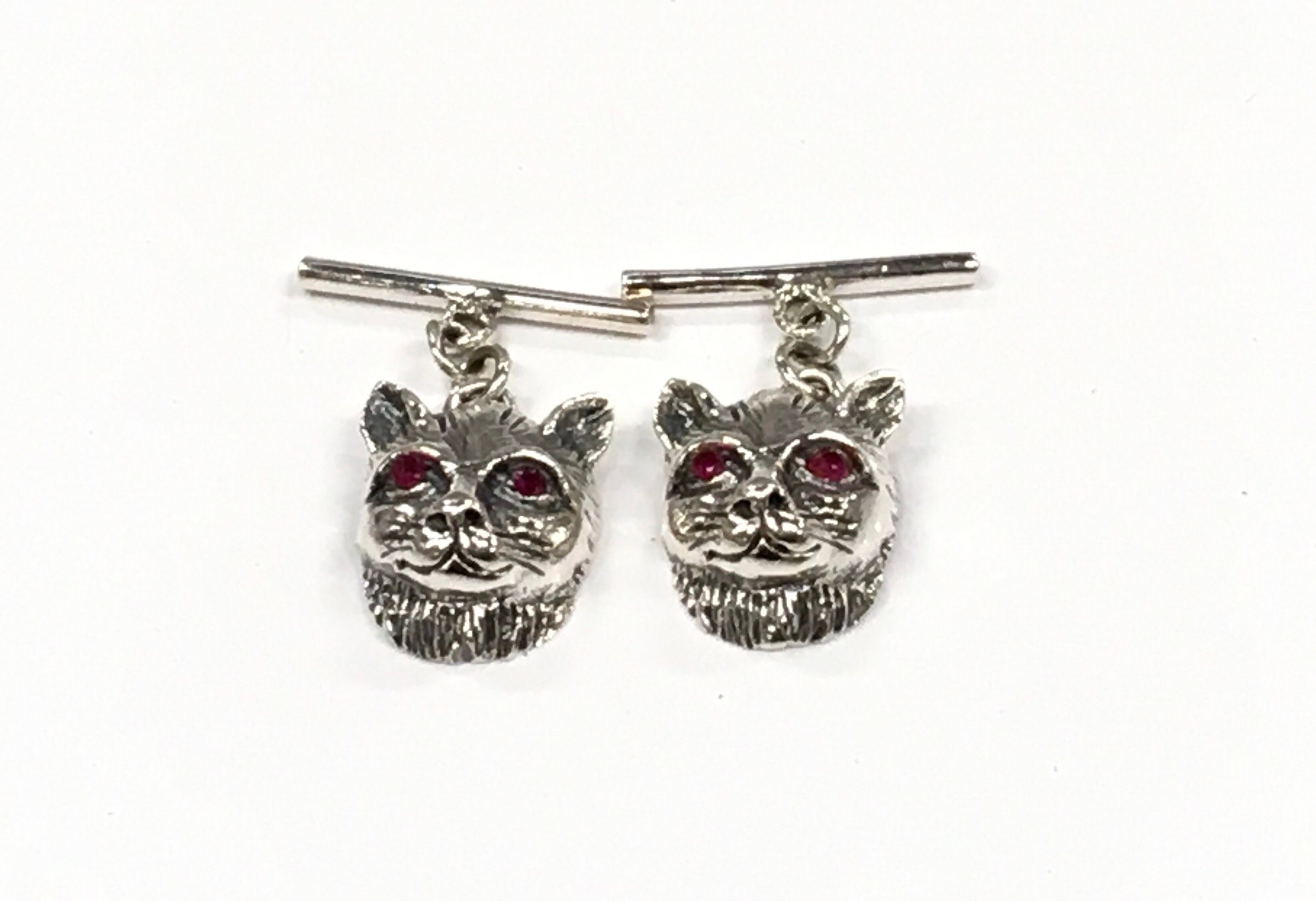 A pair of silver cat head cuff links with bar links.