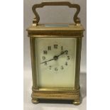 Antique brass carriage clock with enamelled face and bevelled edged glass.