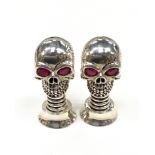 An unusual pair of silver plated scull shaped condiments with ruby eyes.